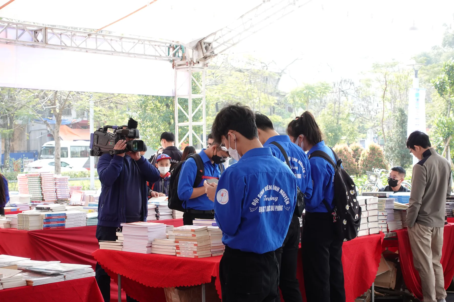 Book stalls along the walkway, student volunteers in blue jackets.